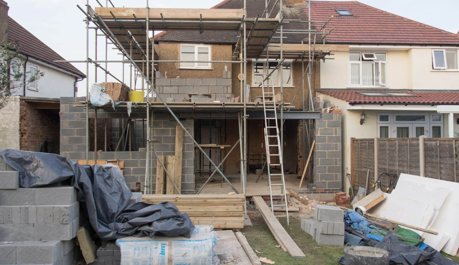 1930s semi-detached house with a rear extension under construction and scaffolding
