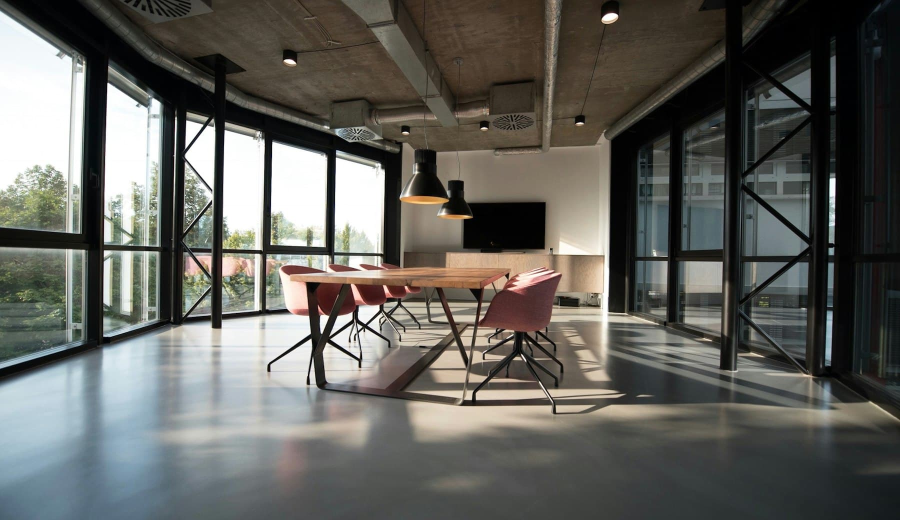 Bright open-plan office with glass walls and a long meeting table